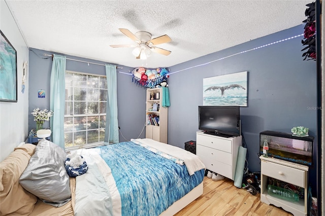 bedroom with ceiling fan, light hardwood / wood-style floors, and a textured ceiling