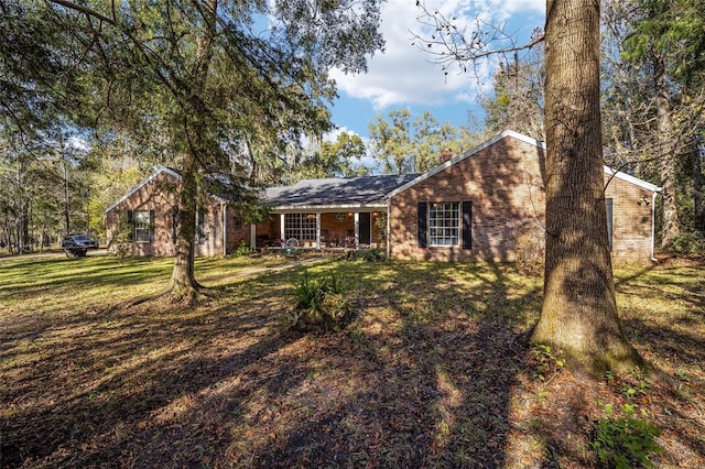 view of front of property featuring covered porch, a front lawn, and brick siding