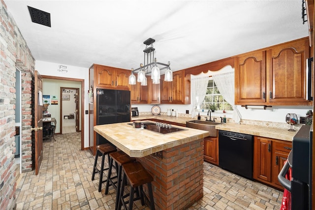 kitchen with sink, pendant lighting, a kitchen bar, a kitchen island, and black appliances