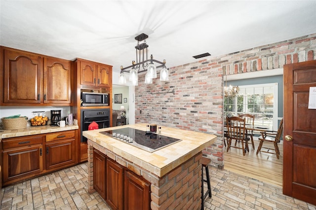 kitchen featuring black appliances, a notable chandelier, a center island, and pendant lighting