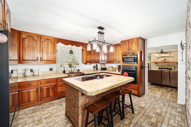 kitchen featuring a breakfast bar, a kitchen island, sink, pendant lighting, and black oven