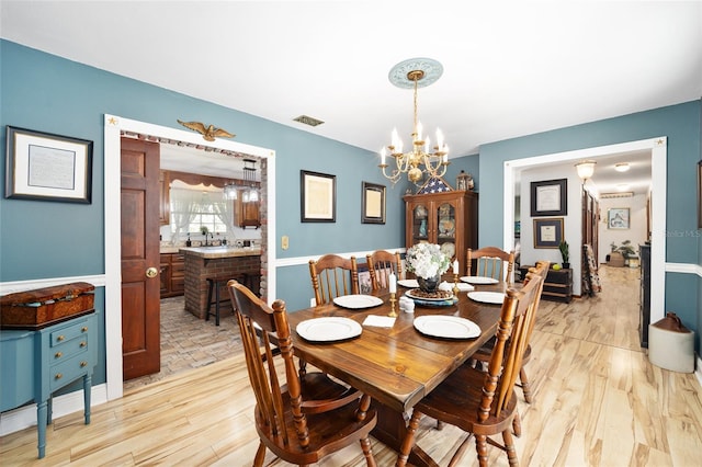 dining area with light hardwood / wood-style flooring and a chandelier