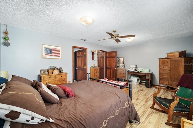 bedroom with ceiling fan, light hardwood / wood-style floors, and a textured ceiling