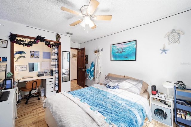 bedroom with ceiling fan, a textured ceiling, and light wood-type flooring