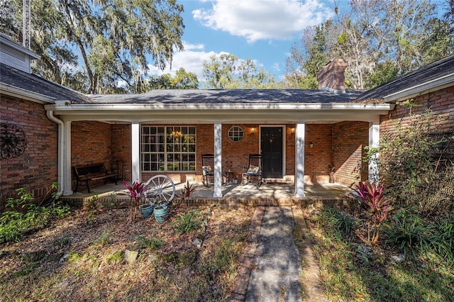 10249 NW 21st St, Ocala, FL 34482 - view of exterior entry with brick siding, a chimney, and covered porch