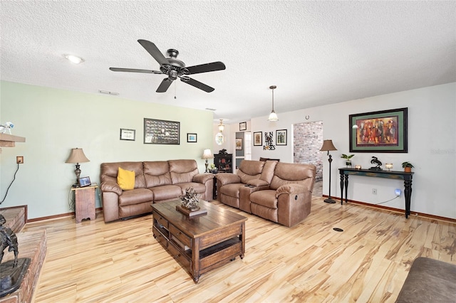 10249 NW 21st St, Ocala, FL 34482 - living room featuring light wood-style floors, a textured ceiling, a ceiling fan, and baseboards