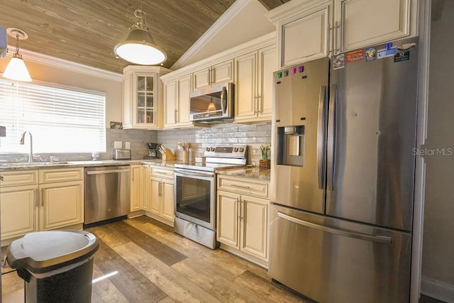 kitchen with light stone counters, hanging light fixtures, stainless steel appliances, lofted ceiling, and sink