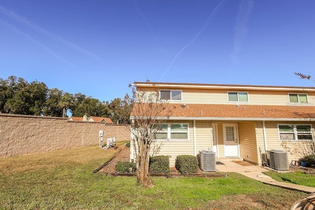 back of house featuring a lawn and central air condition unit