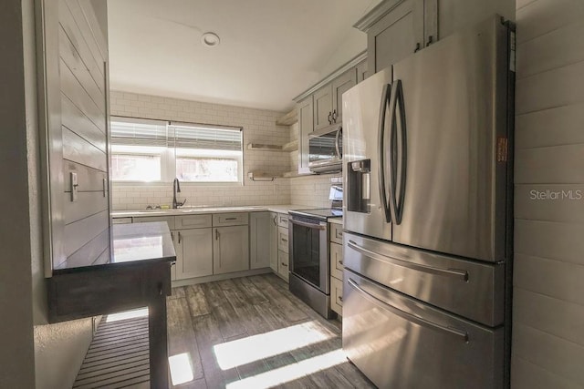 kitchen featuring gray cabinets, appliances with stainless steel finishes, sink, decorative backsplash, and dark wood-type flooring