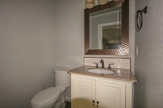 bathroom featuring vanity, backsplash, and toilet