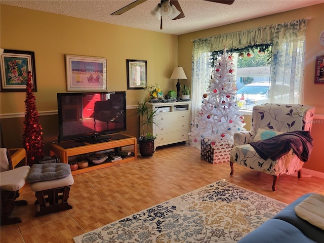 living room featuring ceiling fan, a textured ceiling, and light wood-type flooring