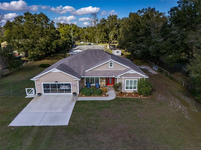 view of front of property with driveway, a shingled roof, an attached garage, fence, and a front yard