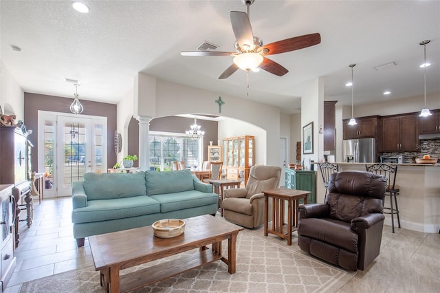 living room featuring decorative columns, arched walkways, ceiling fan with notable chandelier, a textured ceiling, and recessed lighting