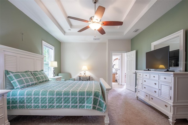 bedroom with light carpet, visible vents, and a tray ceiling