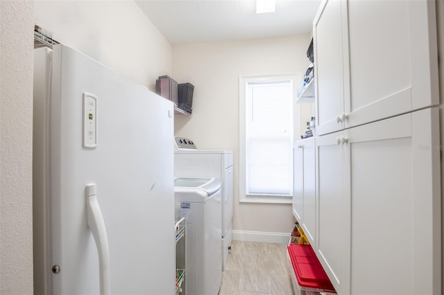 clothes washing area with cabinet space, baseboards, and washer and dryer