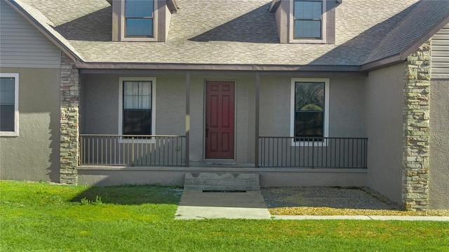 view of exterior entry featuring a porch and a yard