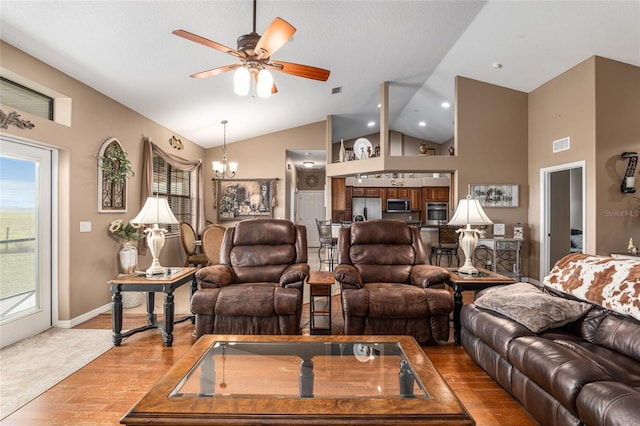 living room featuring vaulted ceiling, light hardwood / wood-style floors, and ceiling fan with notable chandelier