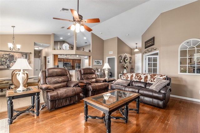 living room with hardwood / wood-style floors, high vaulted ceiling, and ceiling fan with notable chandelier