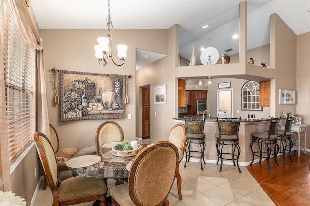 tiled dining area featuring an inviting chandelier and lofted ceiling