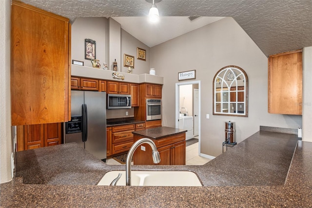 kitchen with sink, washing machine and dryer, high vaulted ceiling, kitchen peninsula, and appliances with stainless steel finishes