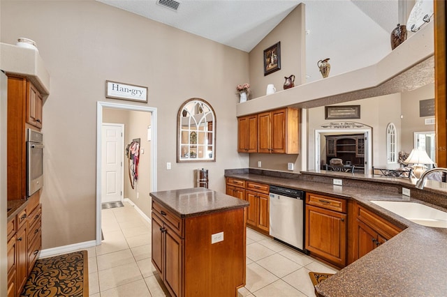 kitchen with sink, a center island, light tile patterned floors, and appliances with stainless steel finishes