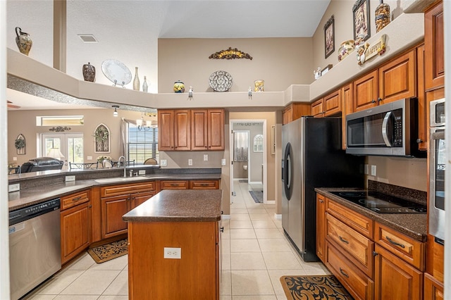 kitchen featuring sink, light tile patterned floors, a towering ceiling, a kitchen island, and stainless steel appliances