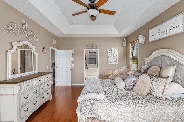 bedroom featuring dark hardwood / wood-style flooring, a tray ceiling, and ceiling fan