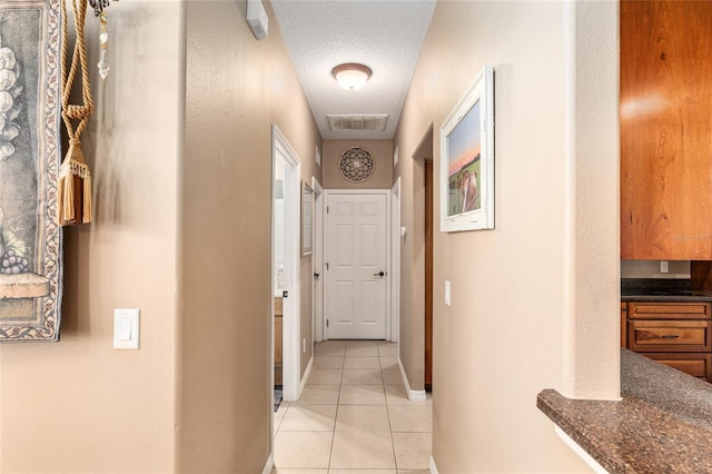 hallway featuring light tile patterned floors and a textured ceiling