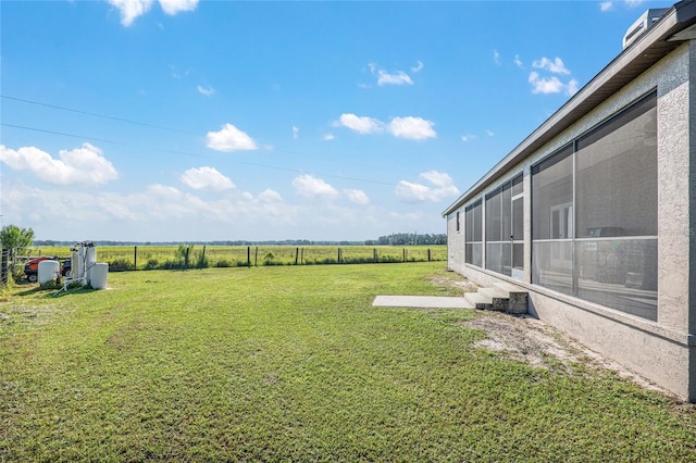 view of yard featuring a sunroom and a rural view