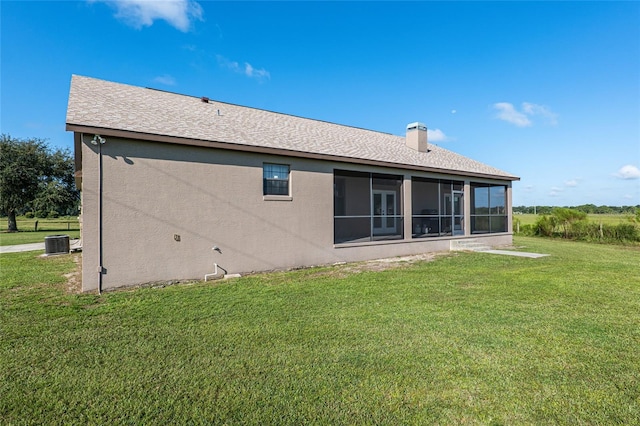 back of house featuring a lawn, a sunroom, and central AC unit