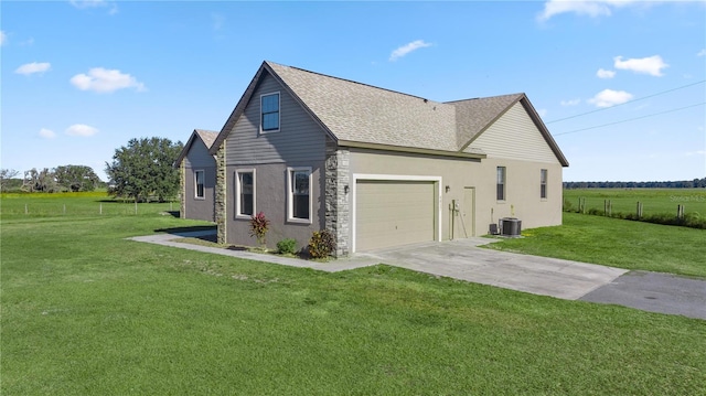 view of home's exterior featuring a lawn, central air condition unit, a rural view, and a garage