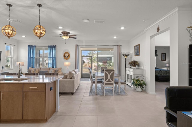 interior space featuring ceiling fan with notable chandelier, sink, ornamental molding, a wealth of natural light, and decorative light fixtures