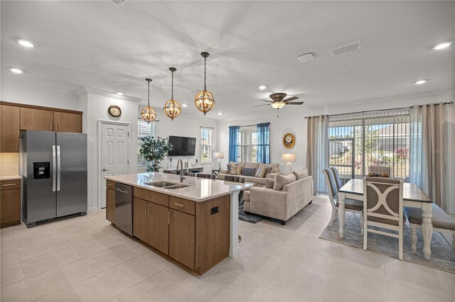 kitchen featuring a wealth of natural light, sink, hanging light fixtures, an island with sink, and appliances with stainless steel finishes