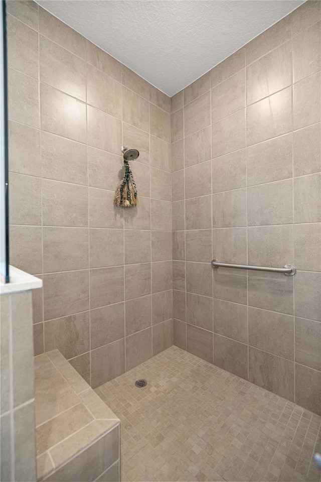 bathroom featuring a textured ceiling and tiled shower