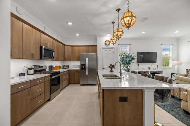 kitchen featuring crown molding, a breakfast bar, open floor plan, a sink, and appliances with stainless steel finishes