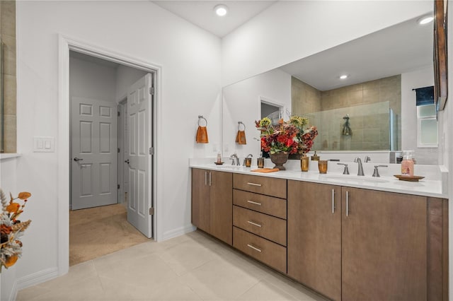 full bath featuring double vanity, tile patterned floors, a tile shower, and a sink