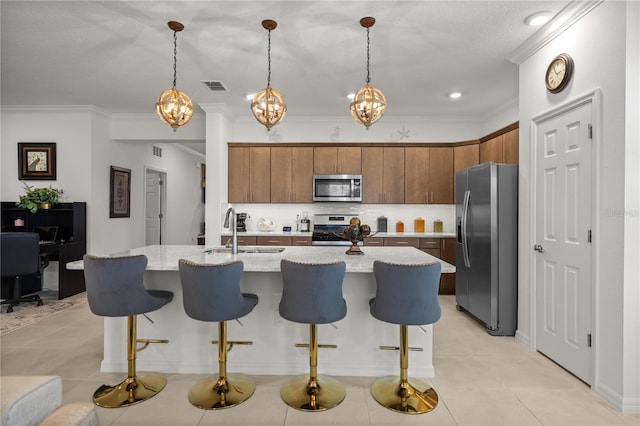 kitchen with visible vents, a breakfast bar area, tasteful backsplash, a sink, and appliances with stainless steel finishes
