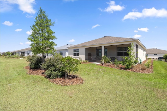 back of house featuring a yard, a sunroom, and stucco siding
