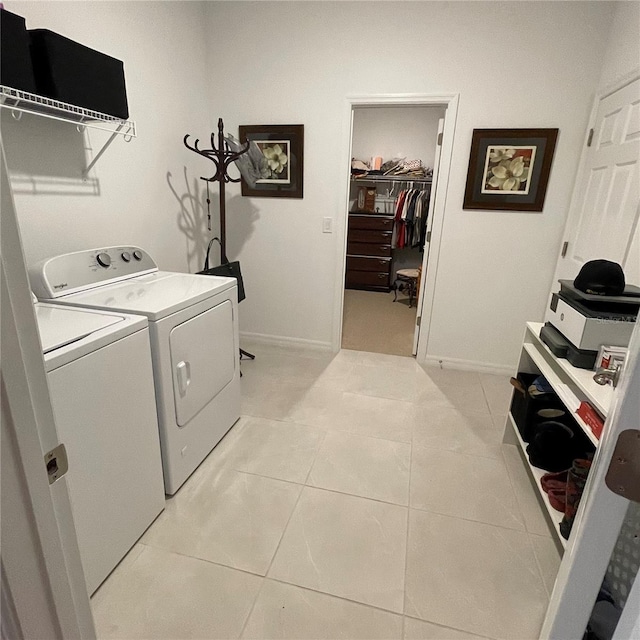 clothes washing area with laundry area, washer and clothes dryer, baseboards, and light tile patterned floors