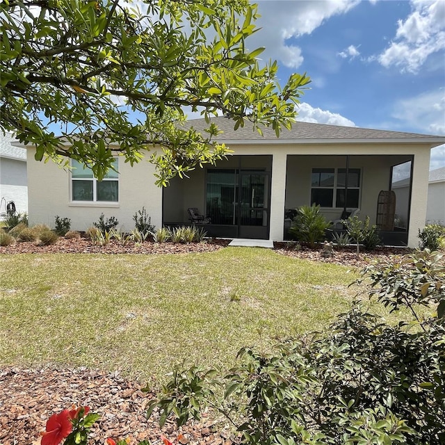 rear view of house featuring a lawn and stucco siding