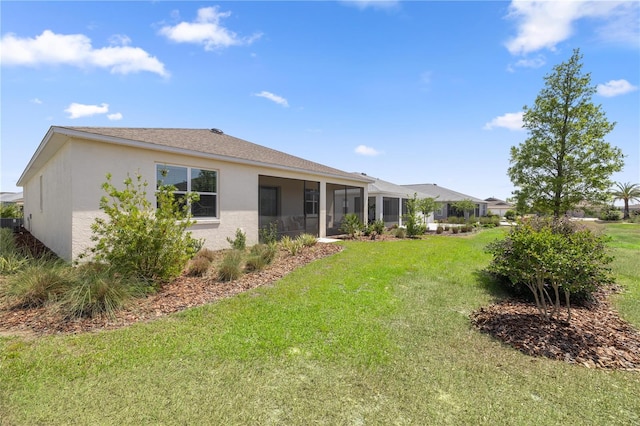 back of property featuring a lawn, a sunroom, and stucco siding