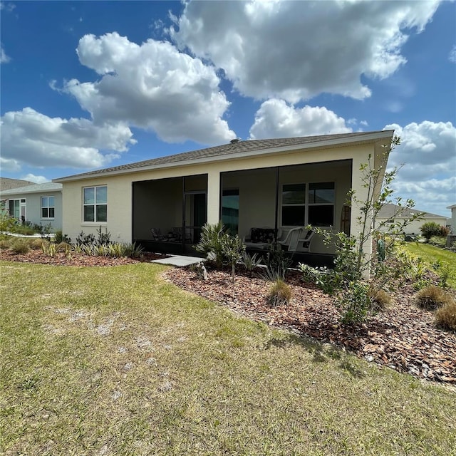 rear view of house with a lawn and stucco siding