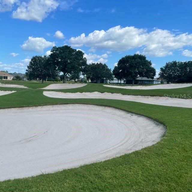 surrounding community featuring a lawn and view of golf course