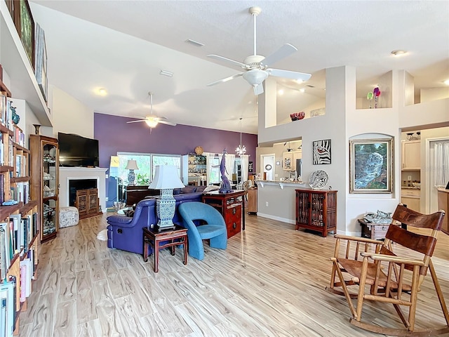 living room featuring ceiling fan, light hardwood / wood-style floors, and high vaulted ceiling