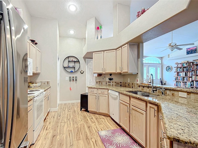 kitchen featuring light stone counters, white appliances, sink, light brown cabinets, and light hardwood / wood-style floors