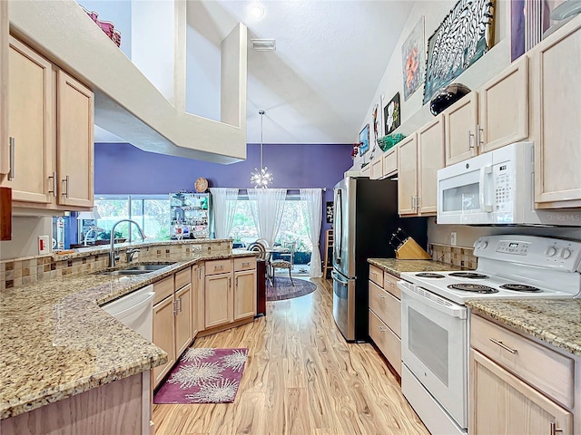 kitchen with light brown cabinets, white appliances, sink, hanging light fixtures, and light hardwood / wood-style flooring