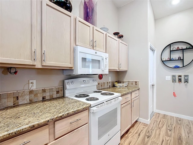 kitchen with light stone countertops, white appliances, light brown cabinetry, and light hardwood / wood-style flooring