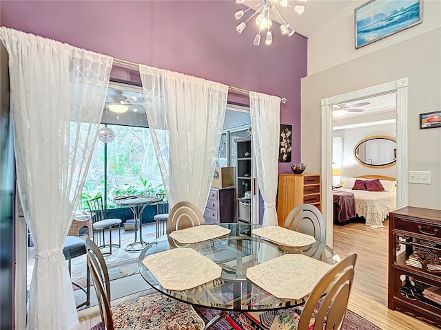 dining space featuring ceiling fan with notable chandelier, light hardwood / wood-style floors, and lofted ceiling