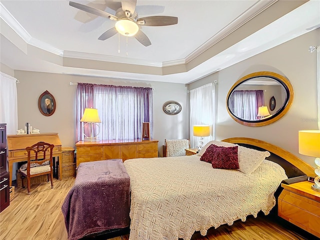 bedroom featuring multiple windows, a raised ceiling, and ceiling fan