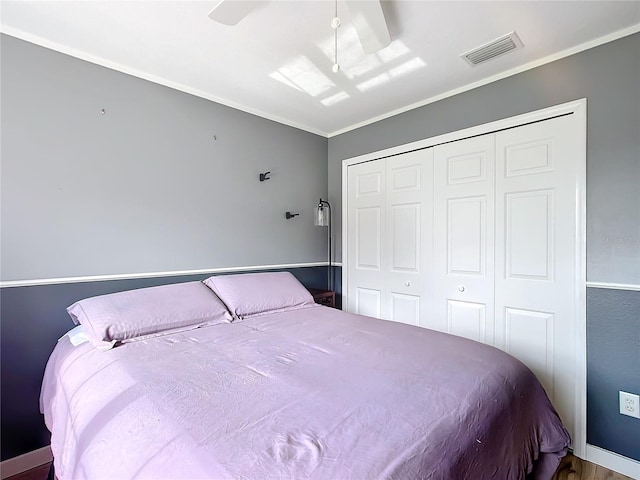 bedroom with a closet, ceiling fan, ornamental molding, and hardwood / wood-style flooring